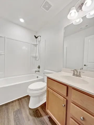a bathroom with a granite countertop sink a toilet a mirror and bathtub
