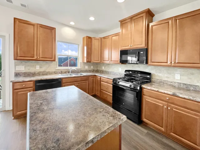 a kitchen with stainless steel appliances granite countertop a stove a sink and a microwave