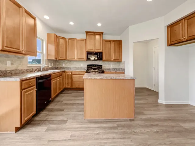 a kitchen with stainless steel appliances granite countertop a stove top oven a sink dishwasher and a refrigerator