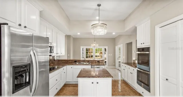 a kitchen with stainless steel appliances granite countertop a refrigerator a oven a stove and a refrigerator with wooden floor