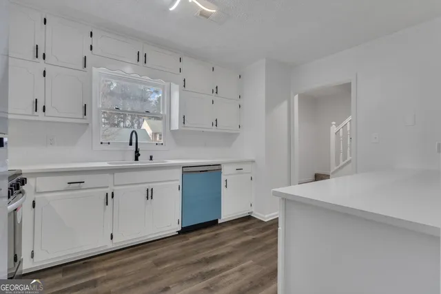a kitchen with white cabinets appliances and a sink