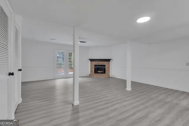 an empty room with wooden floor fireplace and windows