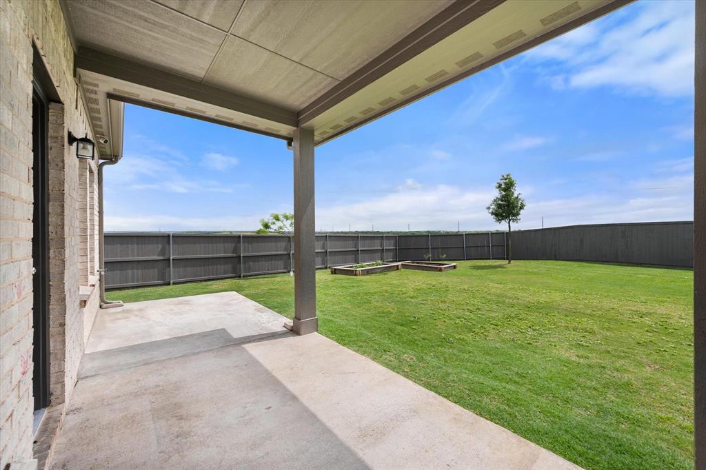 6910 Prairieside Trail Venus, TX 76084 - Photo 35 of 40 The property features a covered patio with a concrete surface, leading to an expansive lawn area