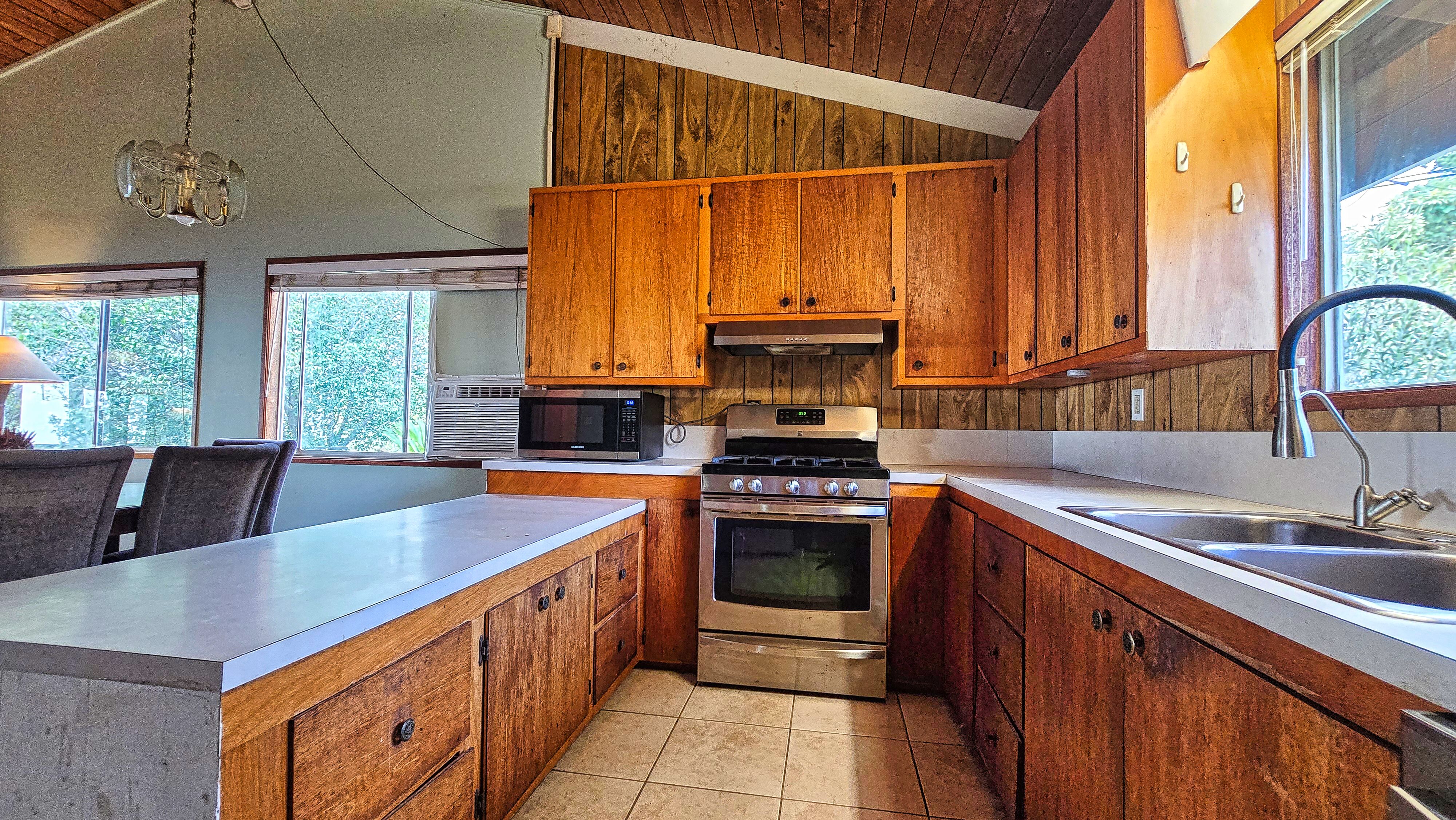 92-8233 Reef Parkway Ocean View, HI 96704 - Photo 11 of 30 a kitchen with stainless steel appliances a sink a stove and a microwave