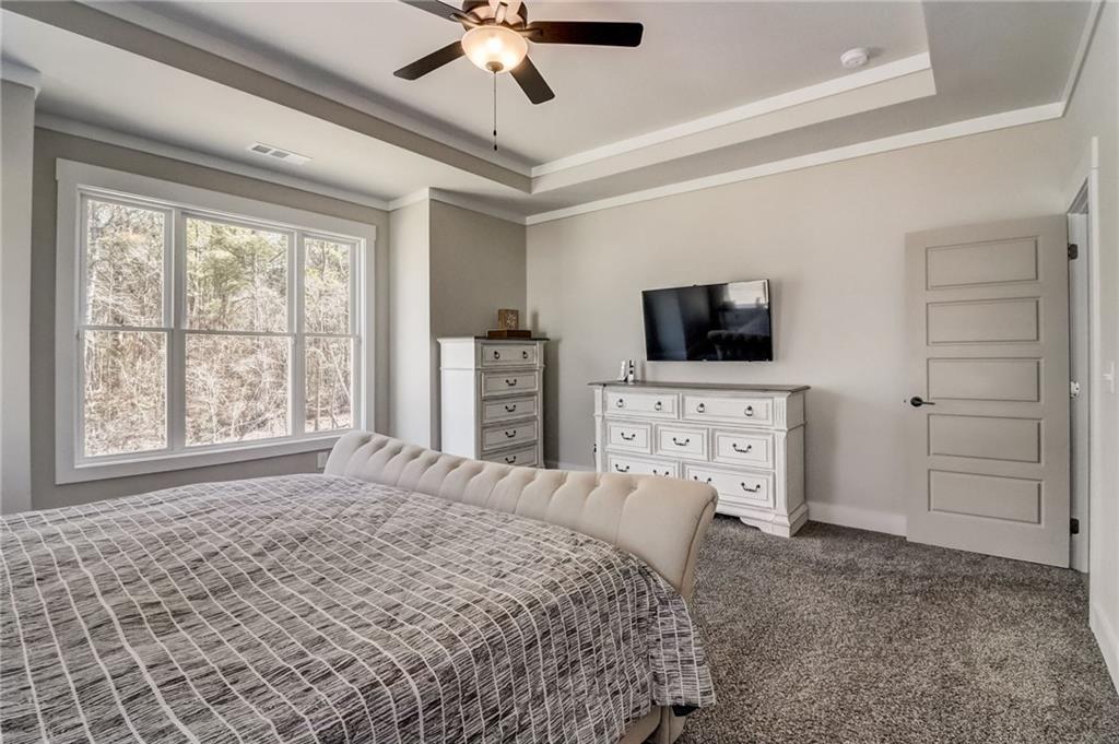 569 White Oak Way Monroe, GA 30655 - Photo 20 of 50 a bedroom with a bed a flat tv screen and a chandelier