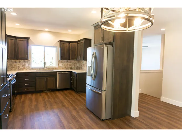 a kitchen with stainless steel appliances a sink cabinets and wooden floor