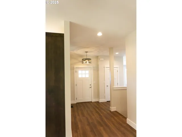 a view of a hallway with wooden floor and a bathroom