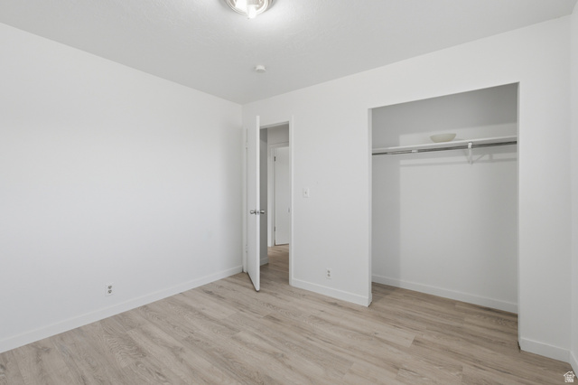 7910 Woolley Way Magna, UT 84044 - Photo 15 of 26 Room featuring light wood-finish flooring, white painted walls, and a ceiling-mounted light fixture