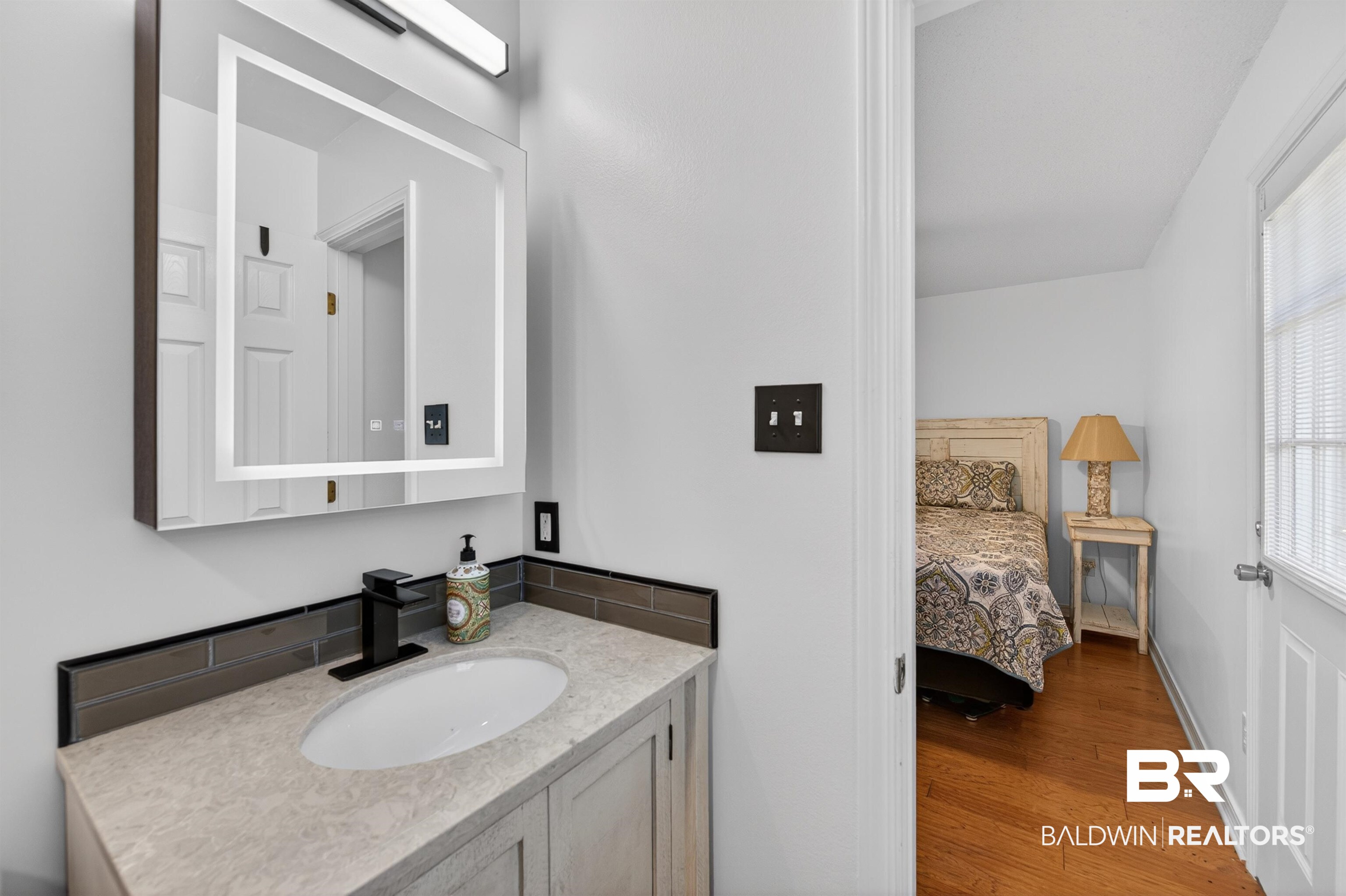 9624 North Bay Street Foley, AL 36535 - Photo 25 of 59 Bathroom vanity featuring a contemporary lighted mirror, undermount sink, and matte black faucet