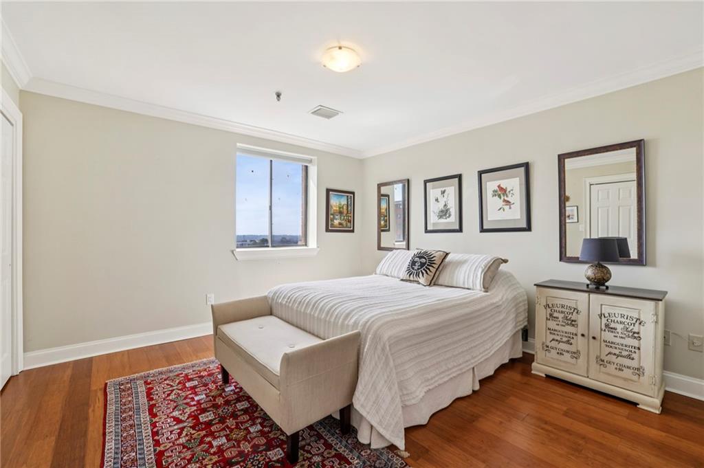 300 Johnson Ferry Road, Unit B804 Sandy Springs, GA 30328 - Photo 16 of 37 a bedroom with a bed and a dresser with wooden floor