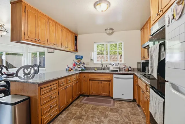 a kitchen with stainless steel appliances granite countertop a sink stove refrigerator and cabinets