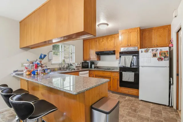 a kitchen with stainless steel appliances granite countertop a sink refrigerator and cabinets