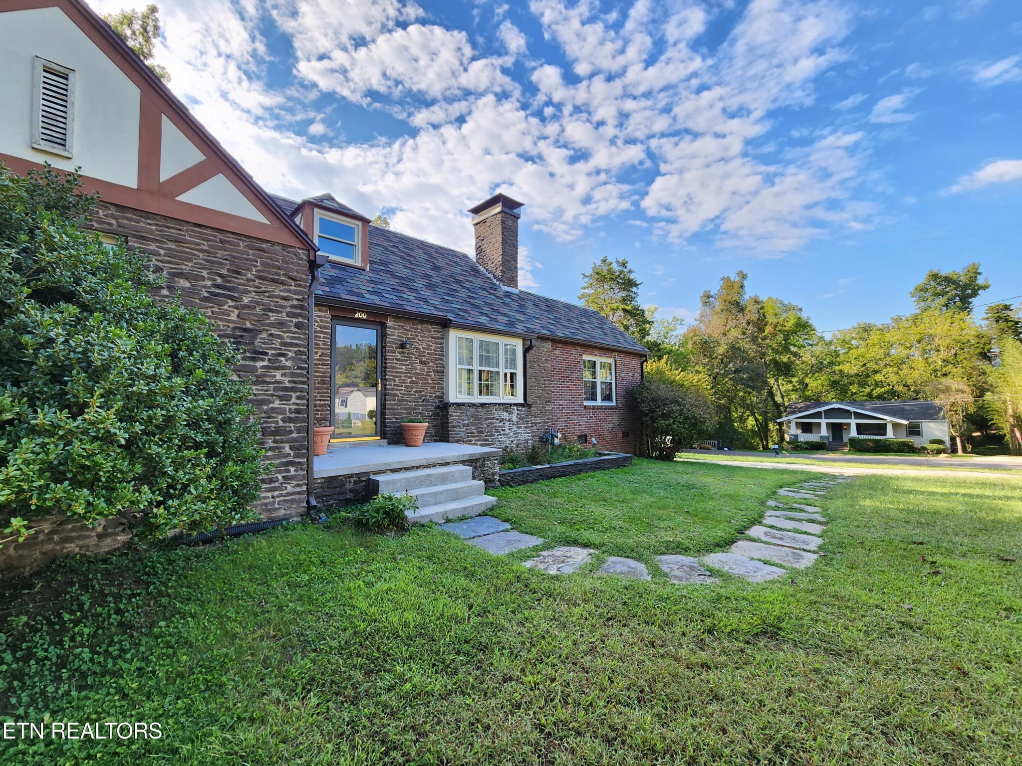 a front view of a house with a yard and trees