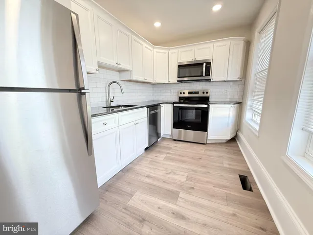 a kitchen with granite countertop a refrigerator stove top oven and sink