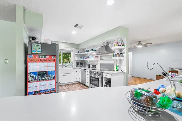 a living room with stainless steel appliances furniture a chandelier and a view of kitchen