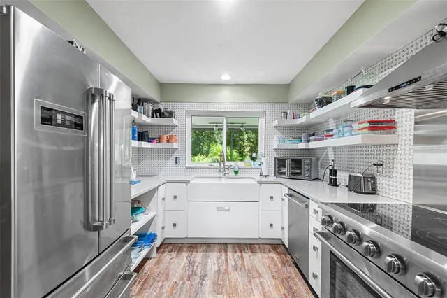 a kitchen with stainless steel appliances a sink a stove and cabinets