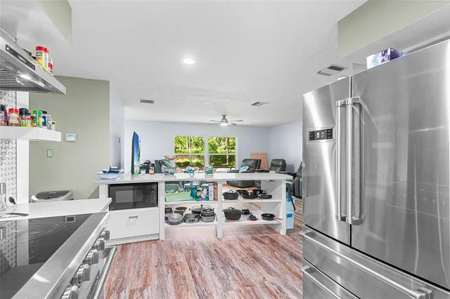 a living room with stainless steel appliances furniture a rug and a kitchen view