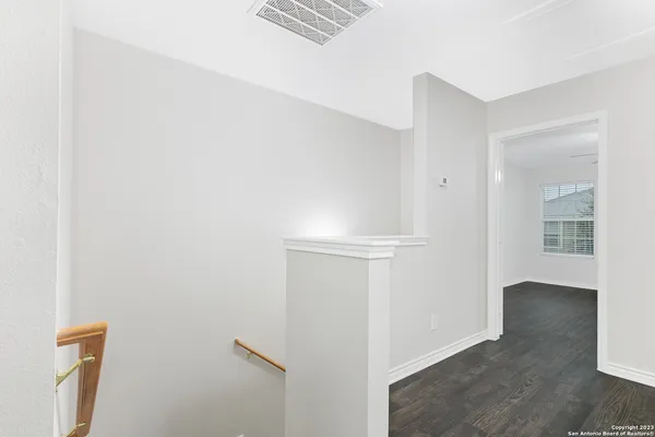 a view of empty room with wooden floor and fan