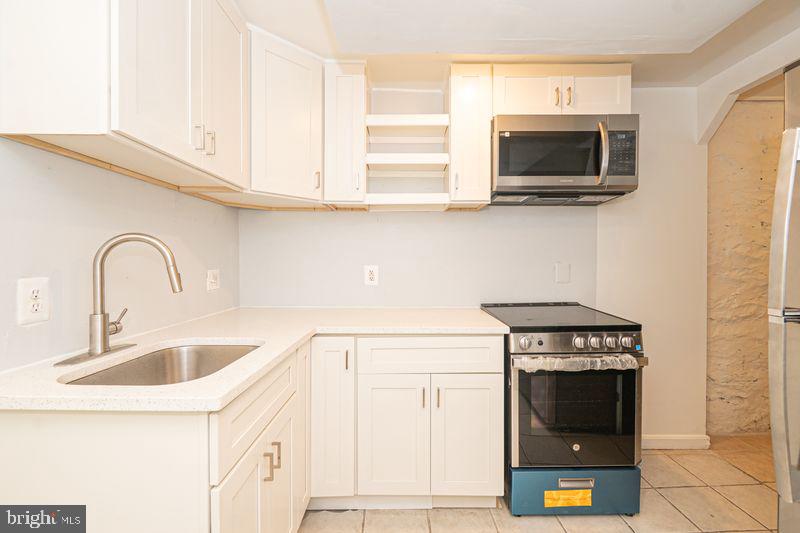307 East 25th Street, Unit BASEMENT APARTMENT Baltimore, MD 21218 - Photo 2 of 21 a kitchen with stainless steel appliances a stove a microwave and sink