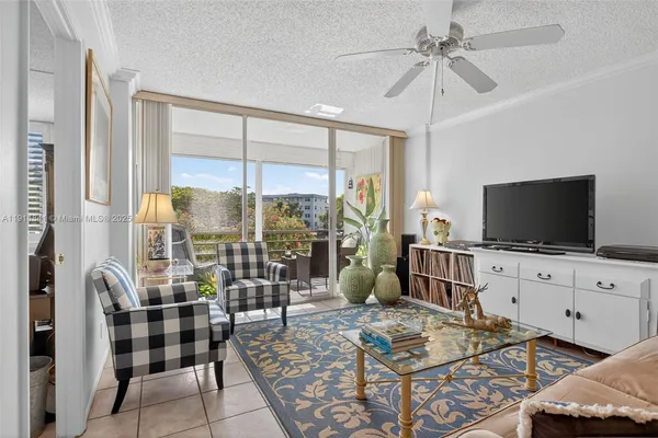 a living room with furniture a flat screen tv and a floor to ceiling window