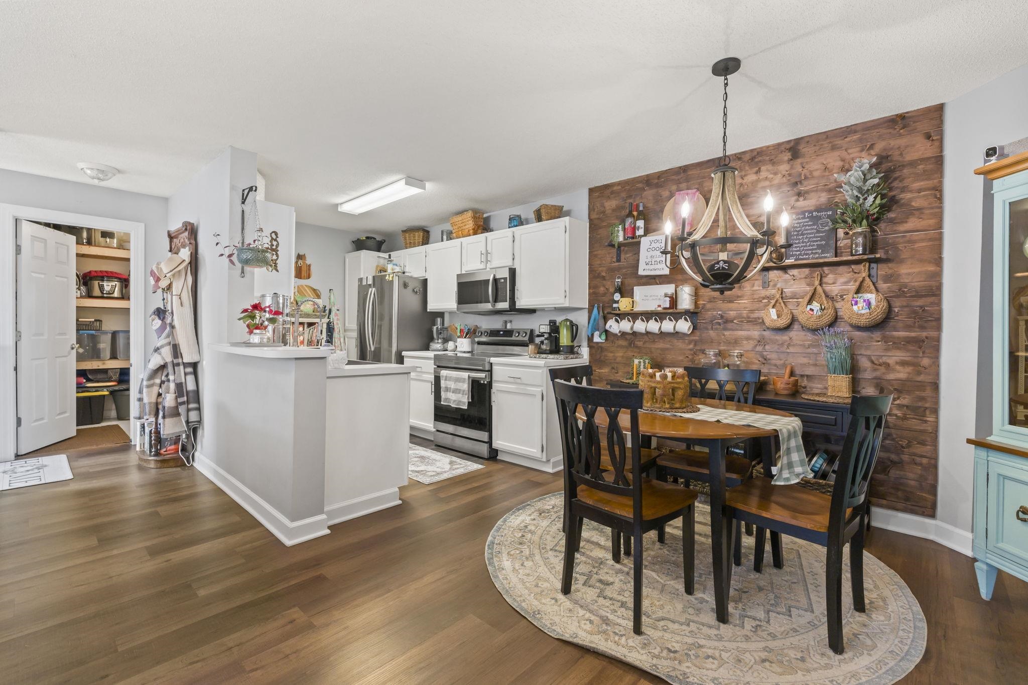 4383 Daphne Lane, Unit F Murrells Inlet, SC 29576 - Photo 8 of 35 Dining area featuring a chandelier, wooden walls, dark wood-style flooring, and an accent wall