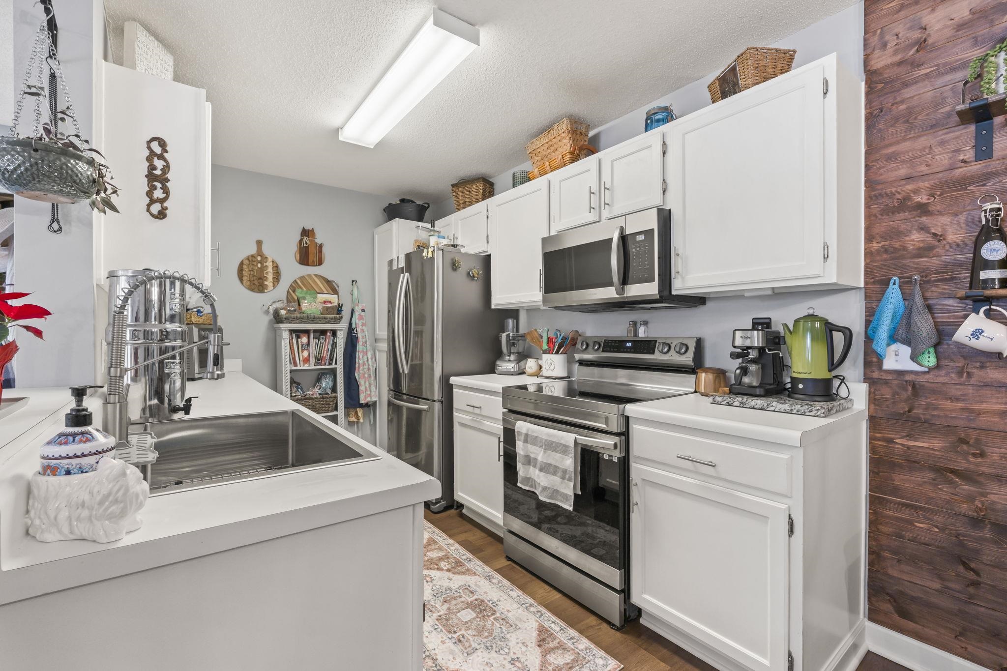 4383 Daphne Lane, Unit F Murrells Inlet, SC 29576 - Photo 9 of 35 Kitchen with appliances with stainless steel finishes, light countertops, white cabinets, a textured ceiling, and light wood finished floors