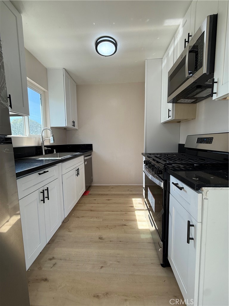 10018 Foster Road, Unit 10020 (1/2) Bellflower, CA 90706 - Photo 3 of 8 a kitchen with stainless steel appliances granite countertop a sink and a stove