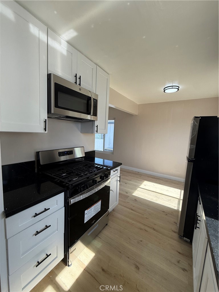 10018 Foster Road, Unit 10020 (1/2) Bellflower, CA 90706 - Photo 7 of 8 a kitchen with stainless steel appliances a stove microwave and sink