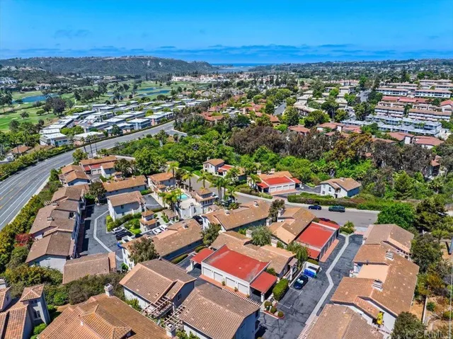 an aerial view of a city with lots of residential buildings ocean and mountain view in back