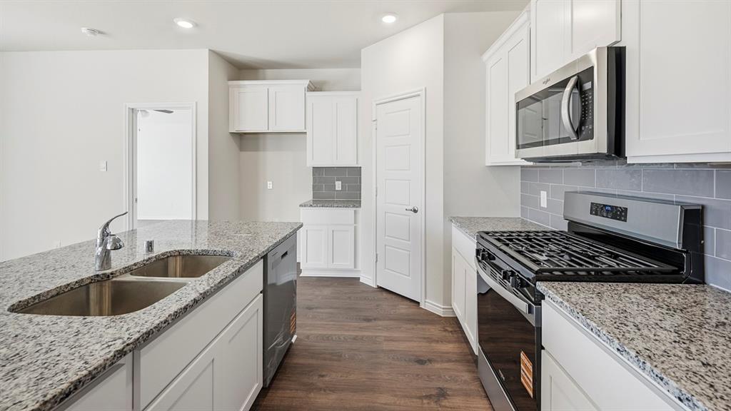 403 Flintlock Road Caddo Mills, TX 75135 - Photo 21 of 26 Kitchen with stainless steel appliances, dark wood-type flooring, white cabinets, decorative backsplash, and light stone counters