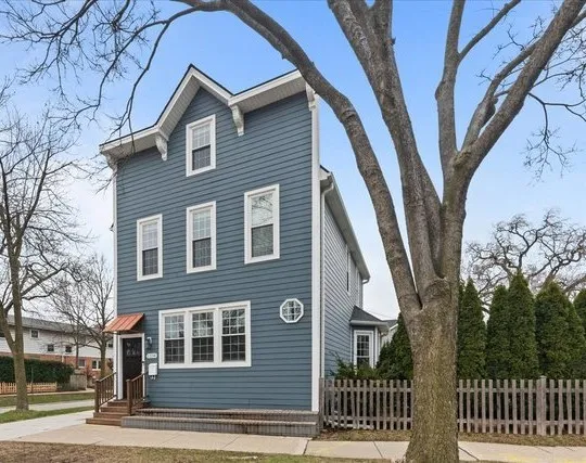 a front view of a house with a tree