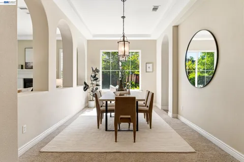 a kitchen with stainless steel appliances granite countertop a stove a refrigerator a kitchen island a dining table and chairs with wooden floor