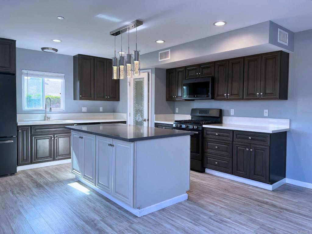 1379 Peach Avenue El Cajon, CA 92021 - Photo 6 of 22 a kitchen with stainless steel appliances kitchen island granite countertop a stove a sink and a microwave