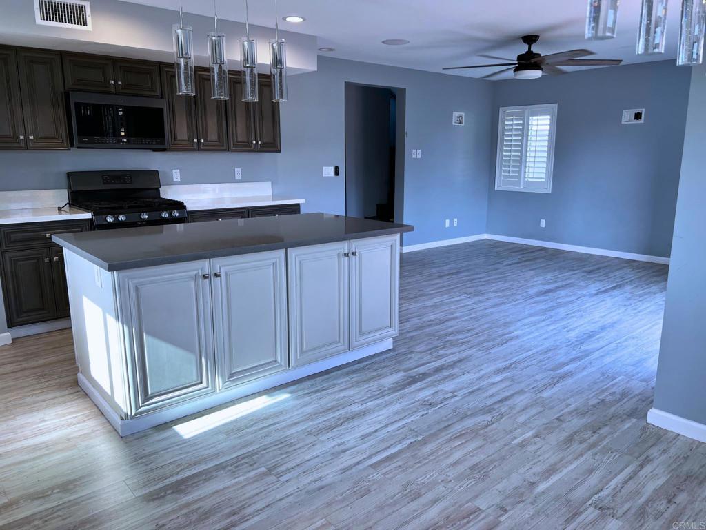 1379 Peach Avenue El Cajon, CA 92021 - Photo 8 of 22 a kitchen with stainless steel appliances wooden floors and wooden cabinets
