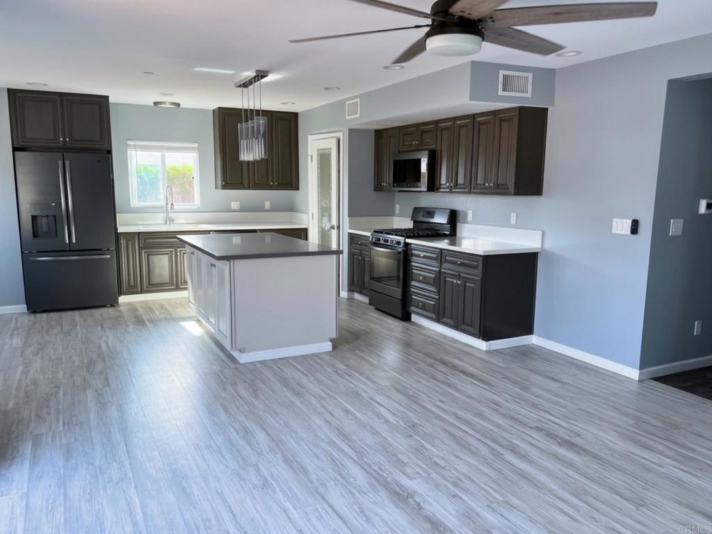 1379 Peach Avenue El Cajon, CA 92021 - Photo 9 of 22 a large kitchen with stainless steel appliances and wooden floor