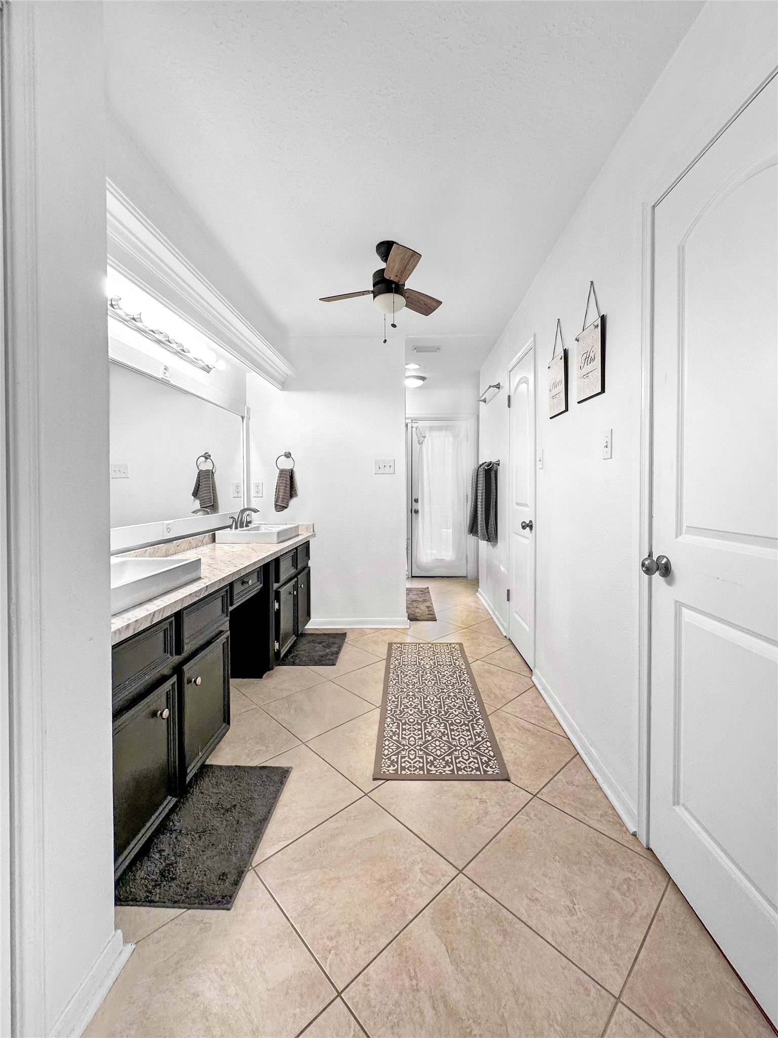 6511 Castle Pine Lane Spring, TX 77379 - Photo 25 of 49 Featuring an expansive vanity with generous counter space, creating both functionality and a luxurious feel. The elongated layout enhances the openness of the suite, while dual walk-in closets — including one oversized closet — provide exceptional storage and organization. Dual closets are thoughtfully designed. Direct access door leads to the backyard oasis.