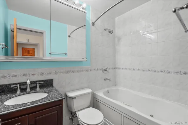 a bathroom with a granite countertop sink a toilet a mirror and bathtub