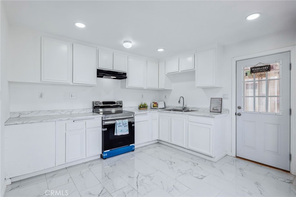 501 B Street Needles, CA 92363 - Photo 10 of 32 a kitchen with granite countertop white cabinets and stainless steel appliances