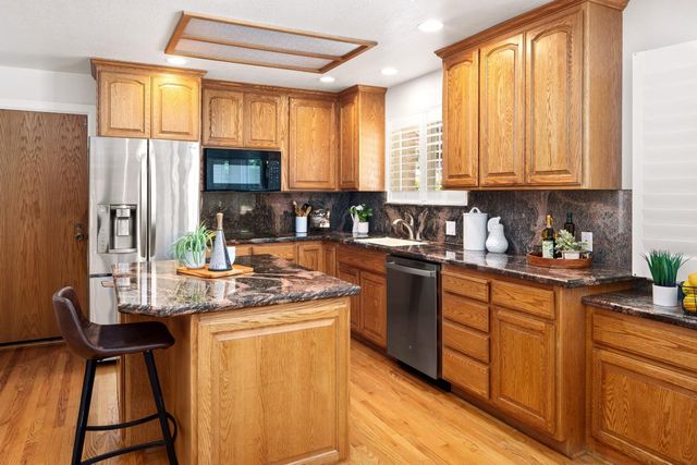 a kitchen with stainless steel appliances granite countertop sink stove top oven and cabinets