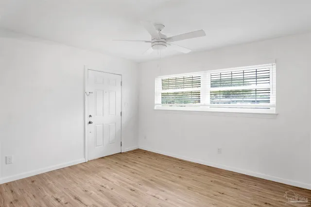 a view of an empty room with wooden floor and a window