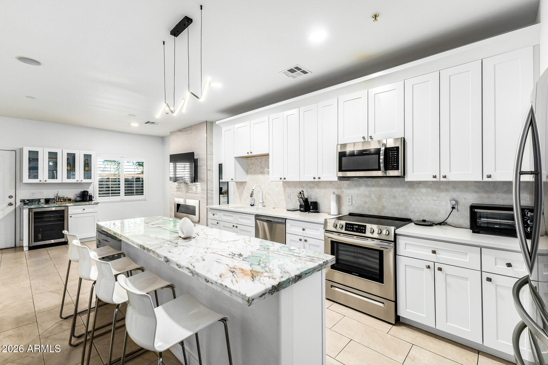 1718 West Colter Street, Unit 115 Phoenix, AZ 85015 - Photo 9 of 26 a kitchen with stainless steel appliances kitchen island granite countertop a stove a sink a microwave a refrigerator and white cabinets with wooden floor