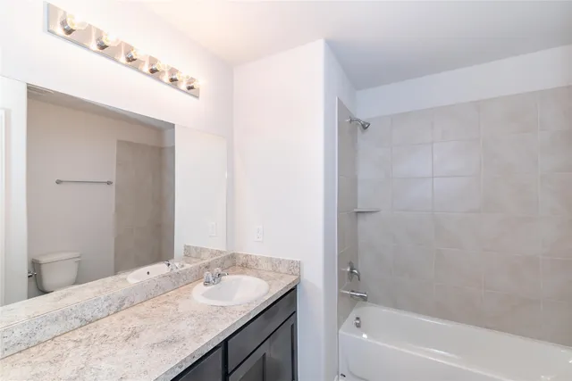 a bathroom with a granite countertop sink a mirror and a bathtub