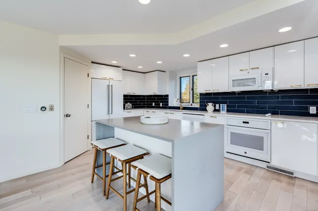 a kitchen with stainless steel appliances granite countertop a stove a sink a refrigerator and white cabinets