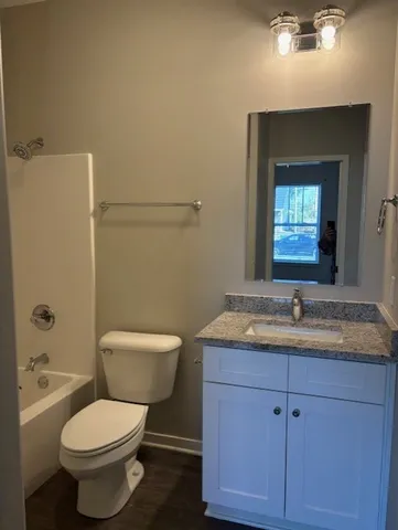 a bathroom with a granite countertop toilet a sink and mirror