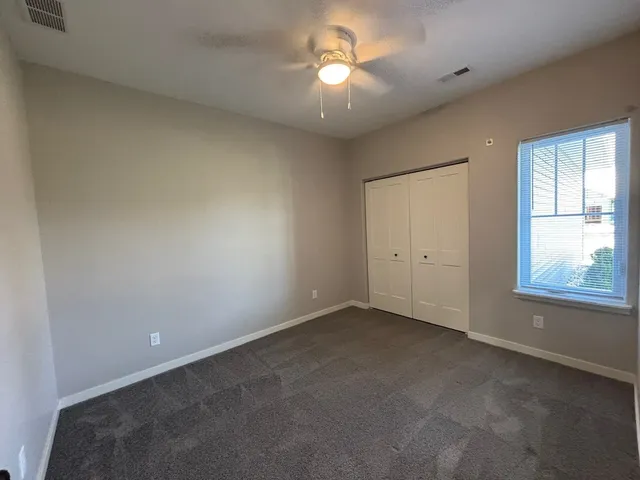 an empty room with a chandelier fan and windows