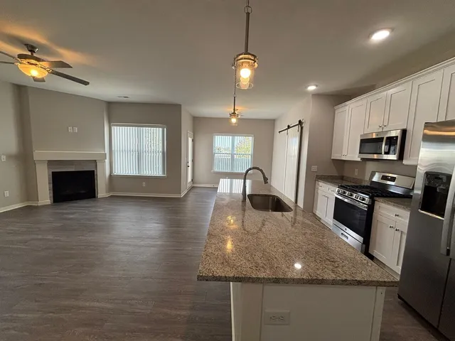 a kitchen with kitchen island granite countertop a stove top oven a sink dishwasher a dining table and chairs with wooden floor