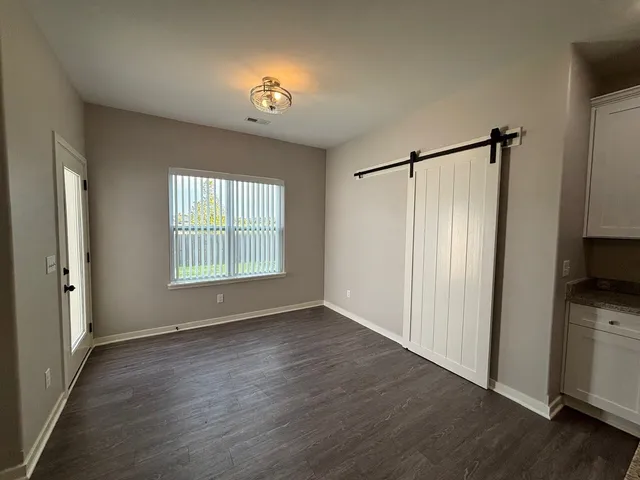 a view of an empty room with a window and wooden floor