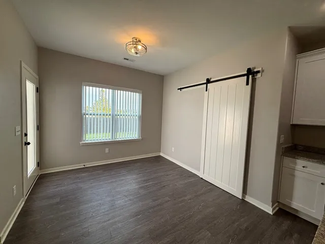 a view of an empty room with a window and wooden floor