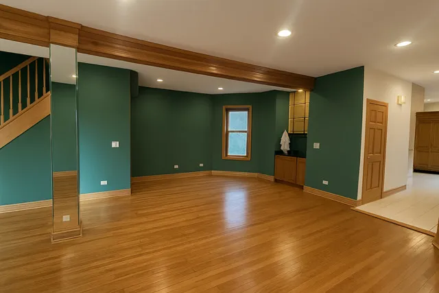 a view of an empty room with wooden floor and a bathroom