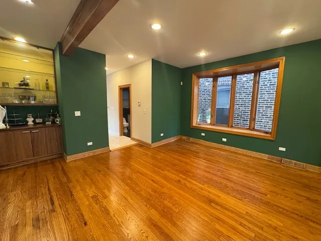 a view of an empty room with window and wooden floor